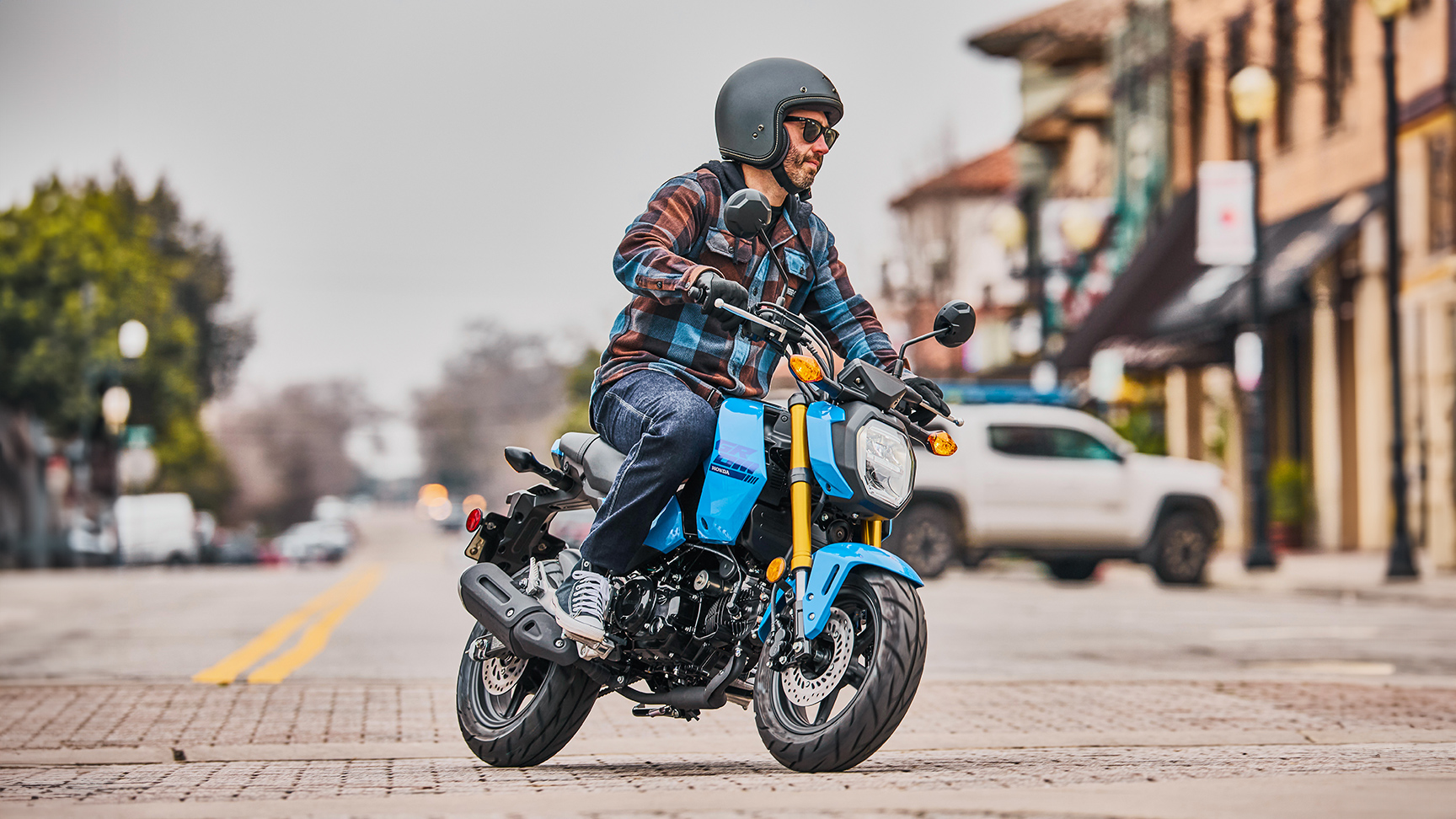 MSX125 Grom – v modrej farbe na ceste, jazdec vchádza do zákruty 