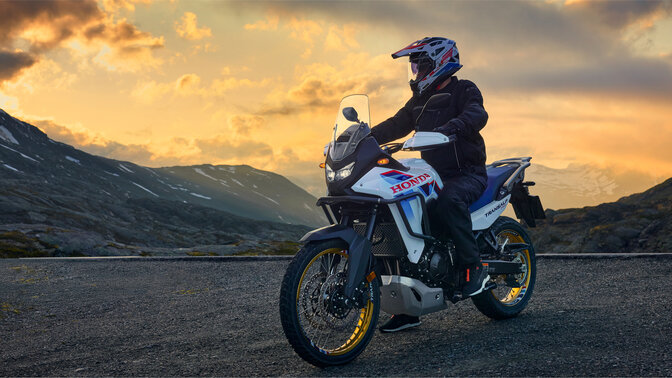 Jazdec jazdiaci na motocykli XL750 Transalp na ceste v horskom prostredí.