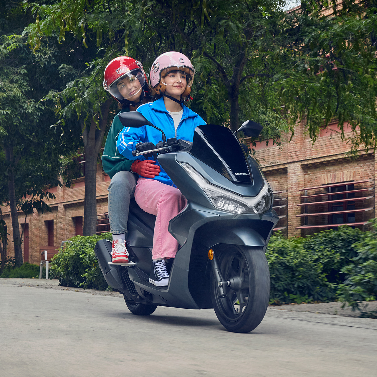 Figuranti pri jazde na motocykli PCX 125 v mestskom prostredí.